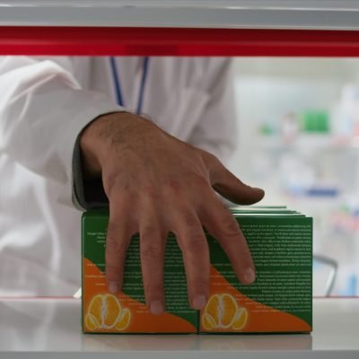 Retail employee emptying racks for products reorganization, taking all medicaments and vitamins in a basket. Seller working on restocking medical products and pharmaceutical supplies. Tripod shot.